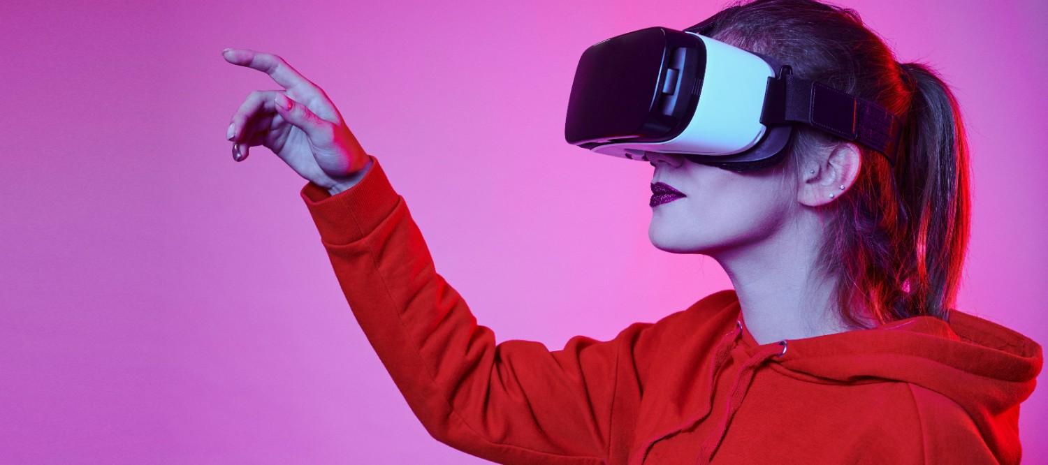 Person wearing a VR headset and red hoodie against a pink background