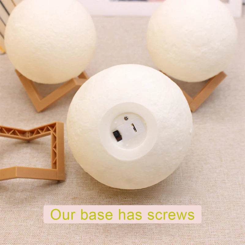 Three moon lamps on a table, two with wooden stands turned off, one lamp without stand showing the base, highlighting the lamp’s base feature
